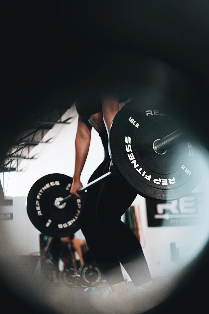 Athlete gripping a loaded barbell in a dark gym