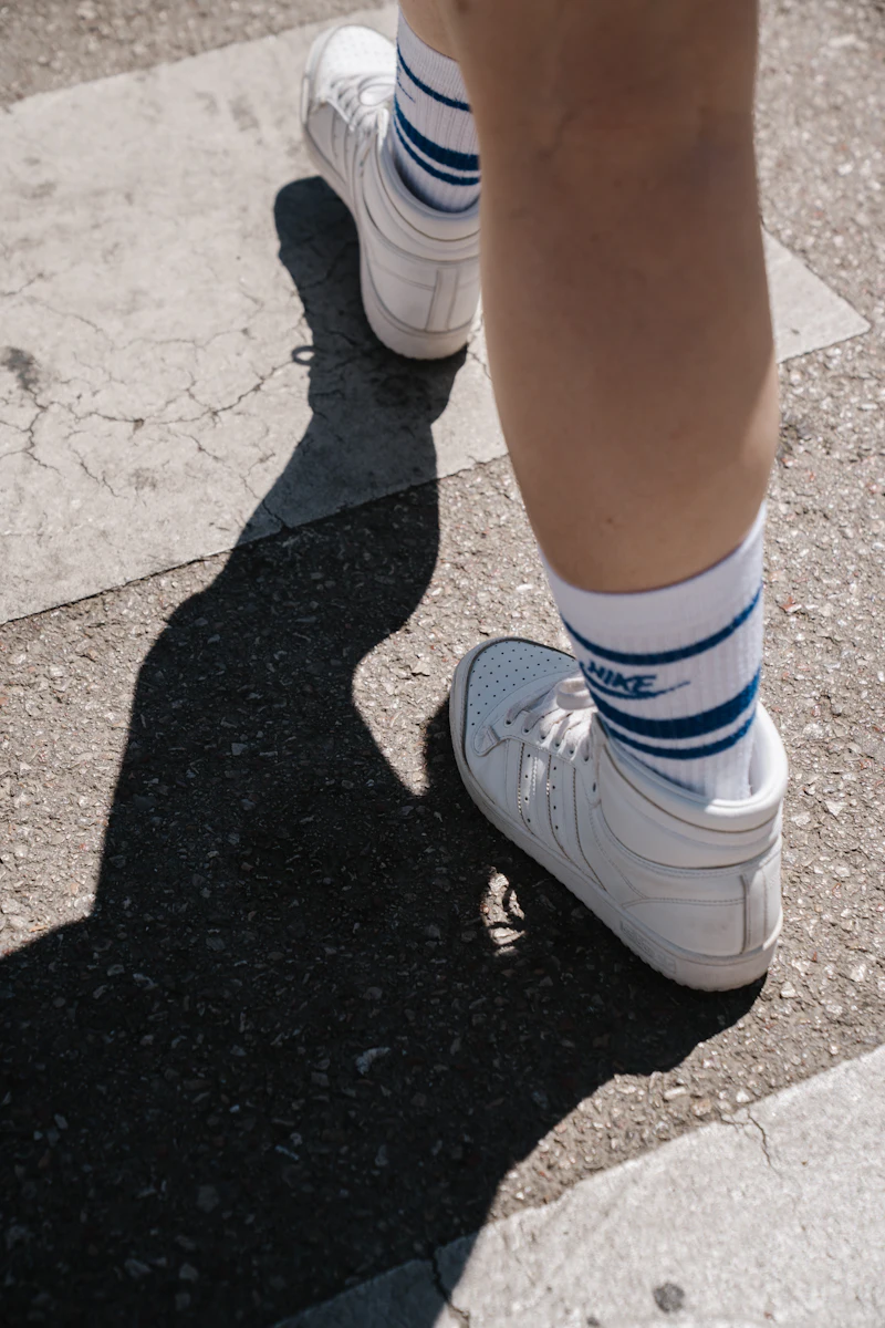 Sneakers casting a long shadow on the pavement