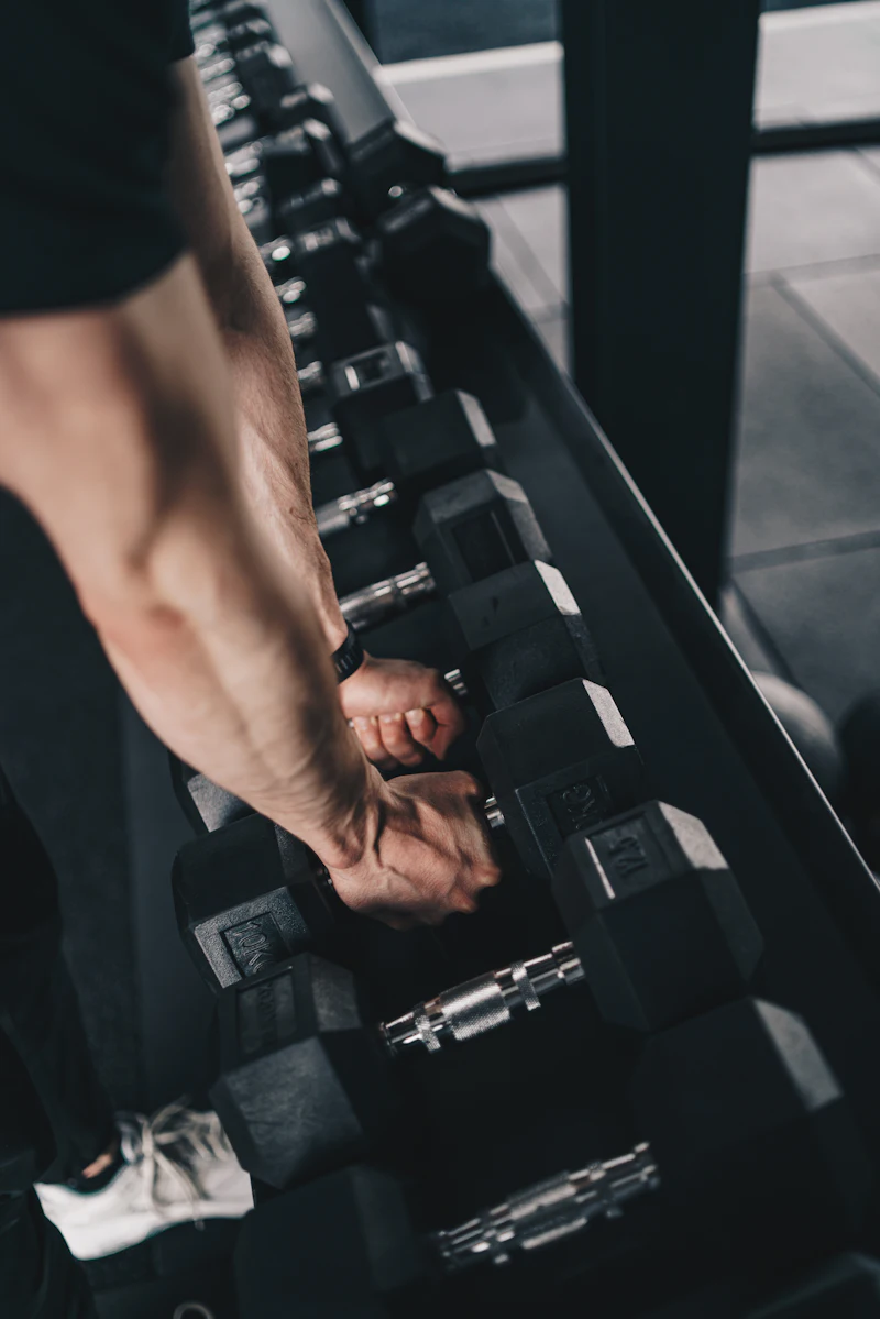 Hand choosing a dumbbell on a gym rack